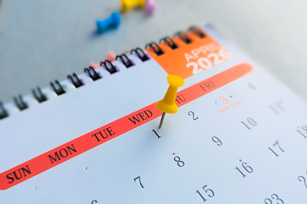 A paper calendar with a thumbtack pinned into it.