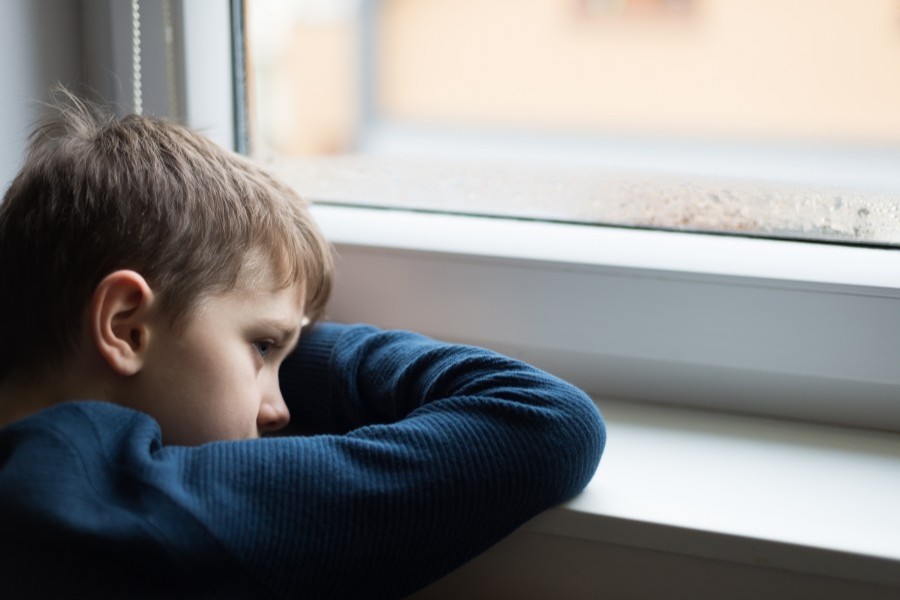 Boy leaning on a window sill, looking out of the window