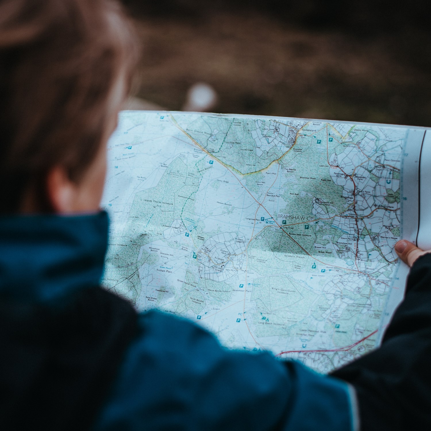 Photograph of a person outdoors reading a map