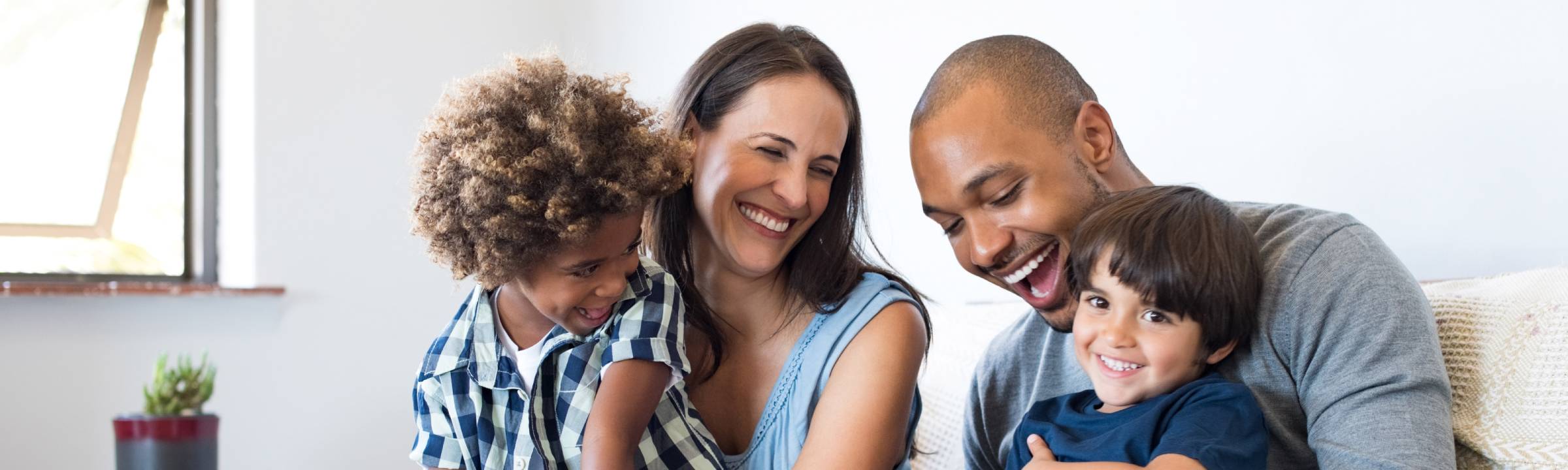 A family sitting together on a sofa and laughing.