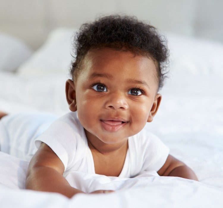 Toddler laying on a bed and looking at the camera