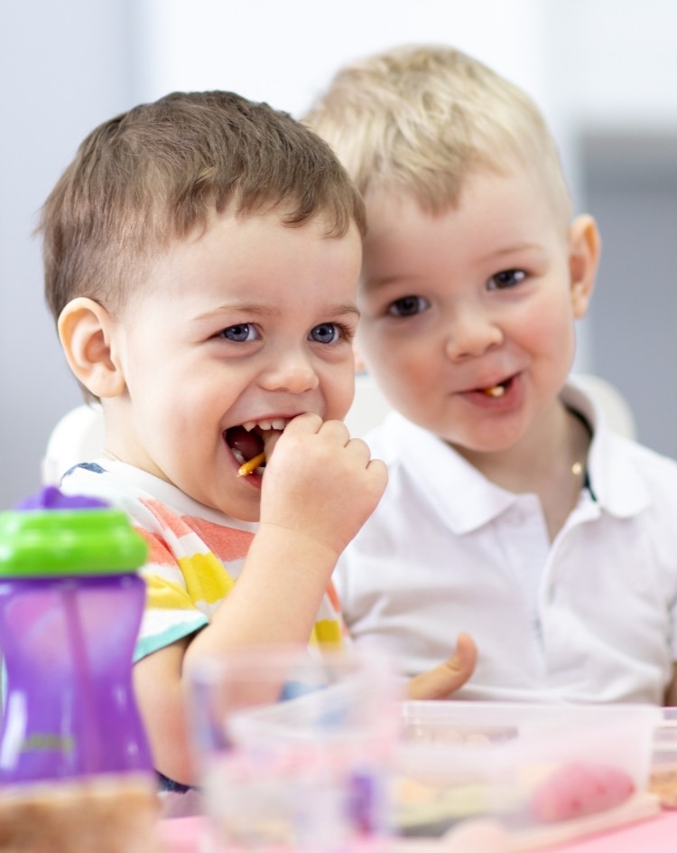 Two cheeky looking boys eating chips