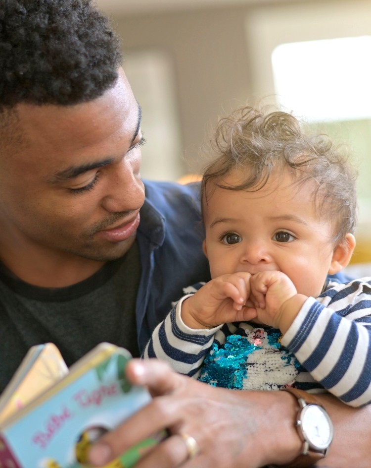 A father looking at a book with his baby