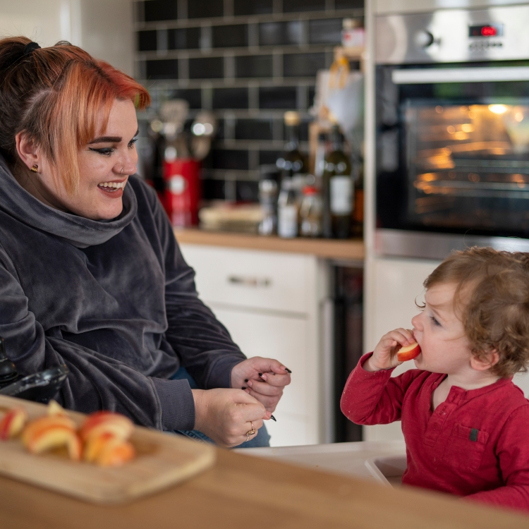 Mother and young daughter in a kitchen eating apple