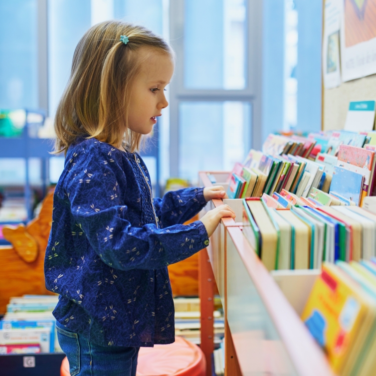 A young girl looking at a collection of books