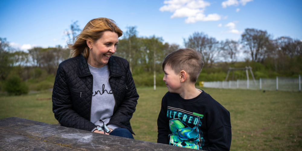 A woman and a young boy sat at a picnic bench