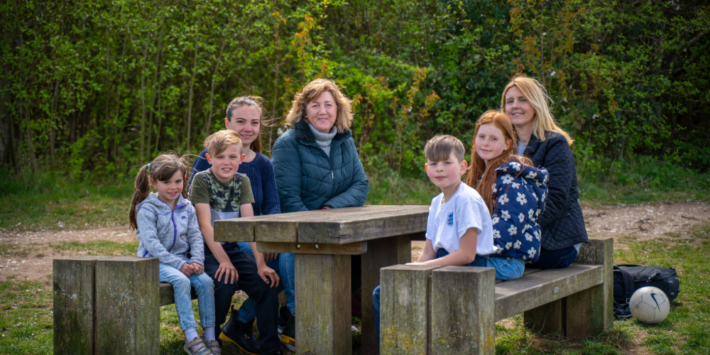A group of adults and children sat around a picnic bench