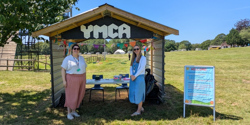 Two people standing outside a YMCA stand in the sun.