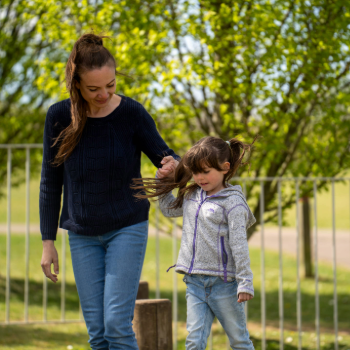 A woman and a young girl walking in a park