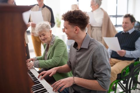 An older woman and younger man playing the piano together