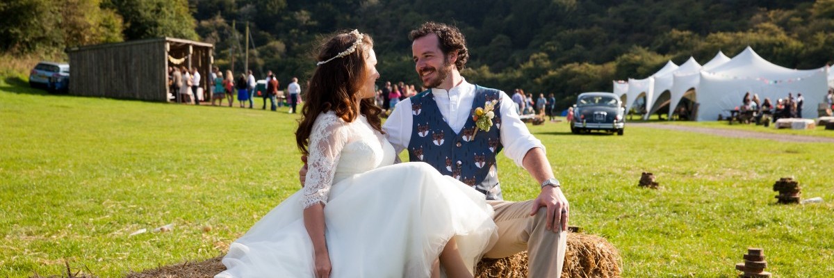 Bride and groom sitting on a hay bale in a field