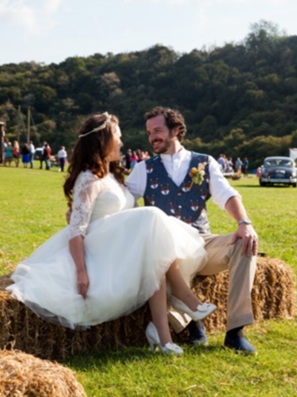 newlywed couple sitting on haybales