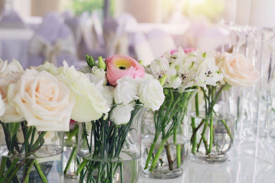 Row of glass vases containing white and pink flowers