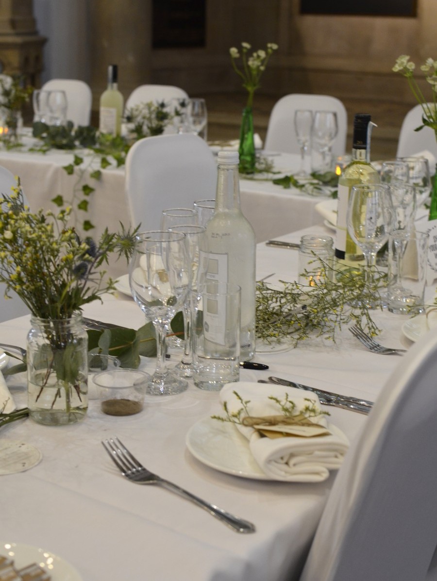 Table dressed for a wedding with while linen, silver cutlery and floral arrangements