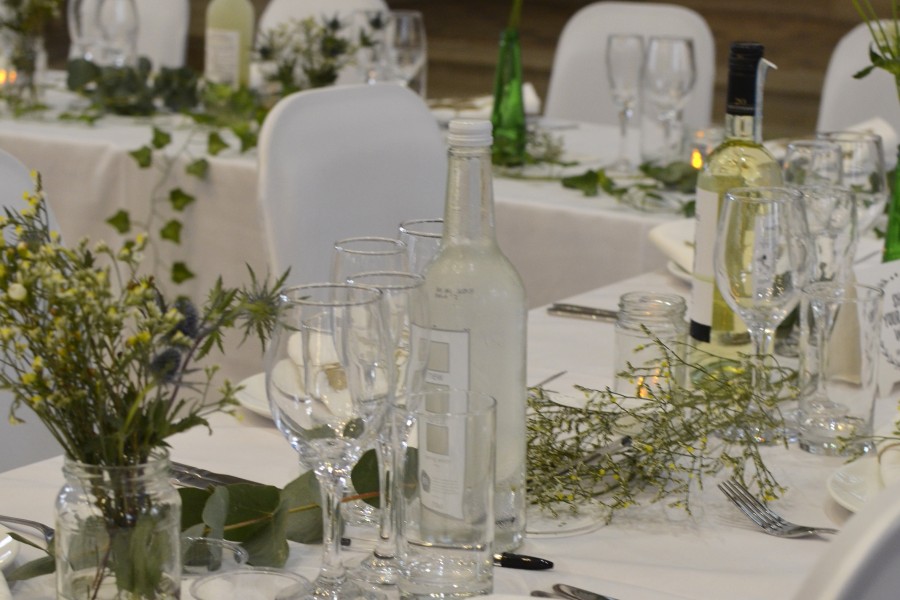 Table dressed for a wedding with while linen, silver cutlery and floral arrangements