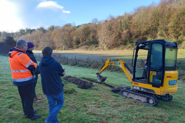 A group using an excavator while doing maintenance in the countryside.