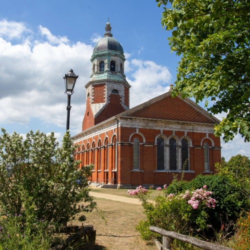 A long shot of Royal Victoria Chapel surrounded by green trees, bushes and blue sky.