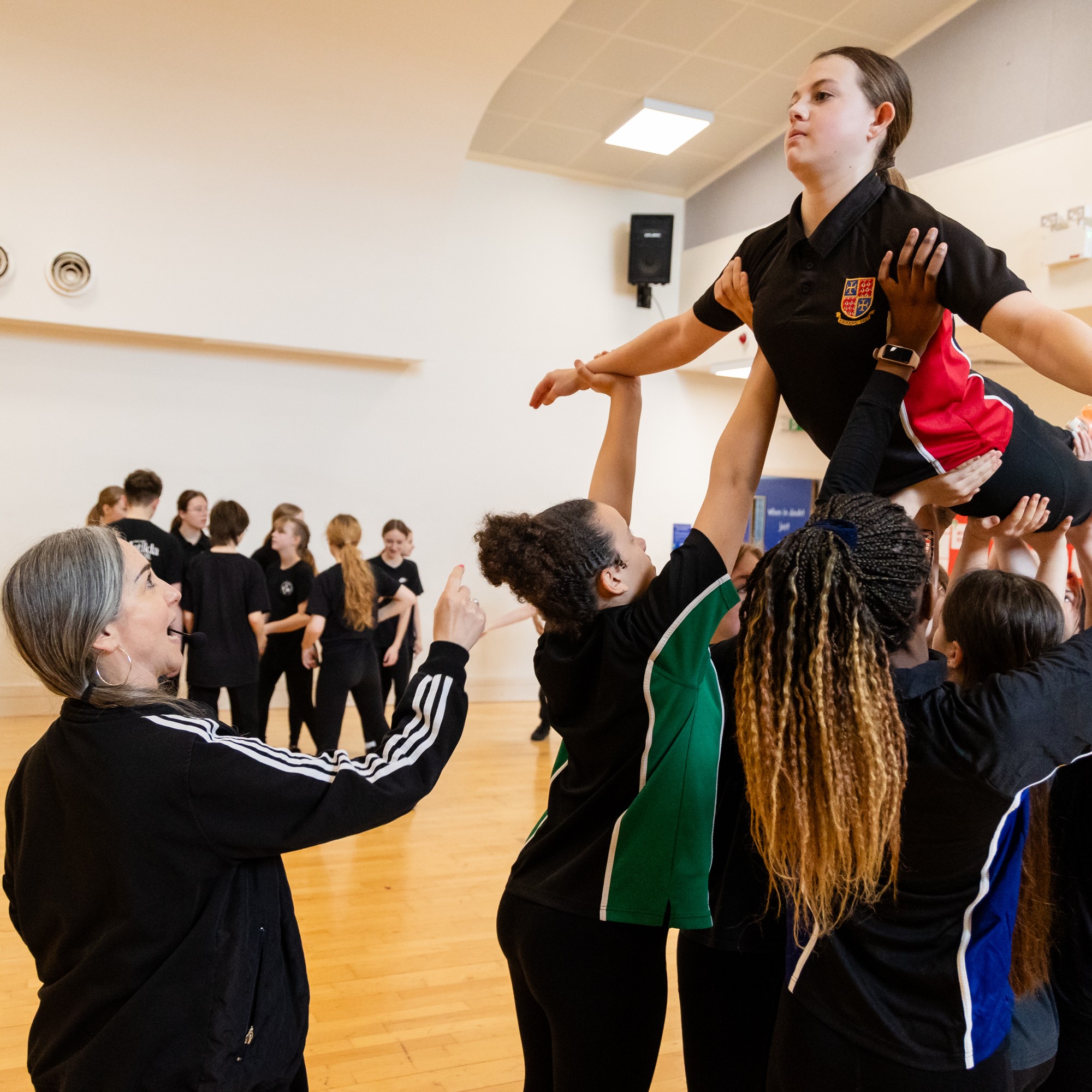 Young people lifting a young girl above their heads in a dance studio