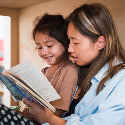 Mother reading to daughter in reading nook