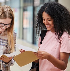 Image shows two girls opening their exam results