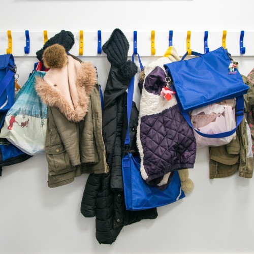 image shows line of coat pags containing school bags and jackets