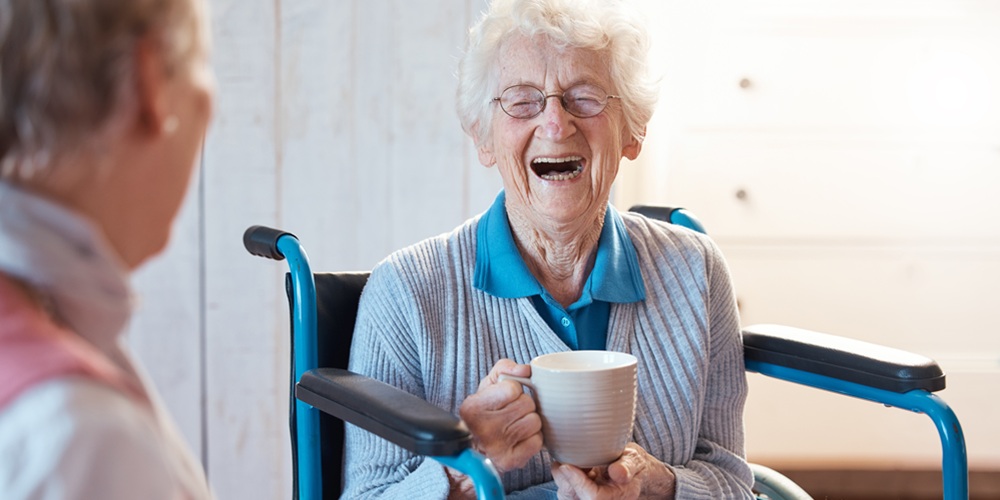 Two older women chatting and smiling in a care setting