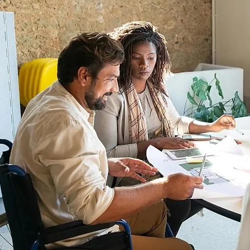 Two people sitting at a table looking at work documents