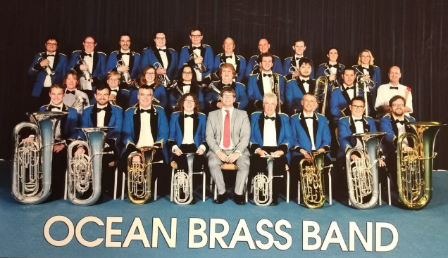 A picture of Ocean Brass band players sat in rows with their instruments