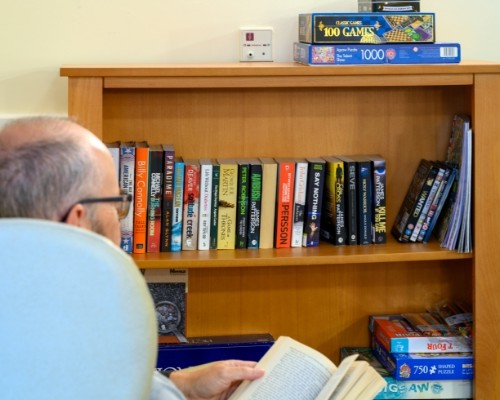 Photo of a resident reading in front of a bookshelf at Woodcot Lodge