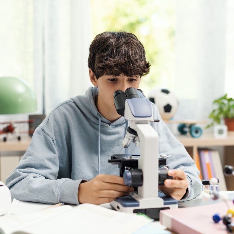 Teenage boy looking into a microscope