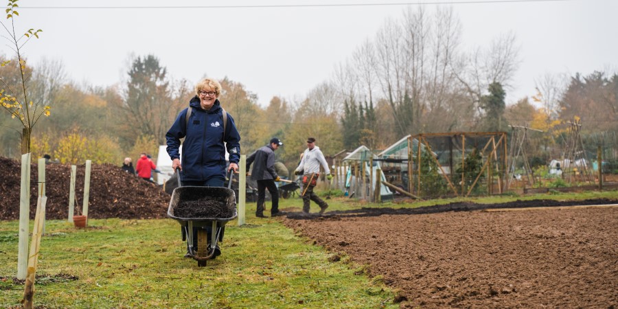 Woman walking with a wheelbarrow full of soil