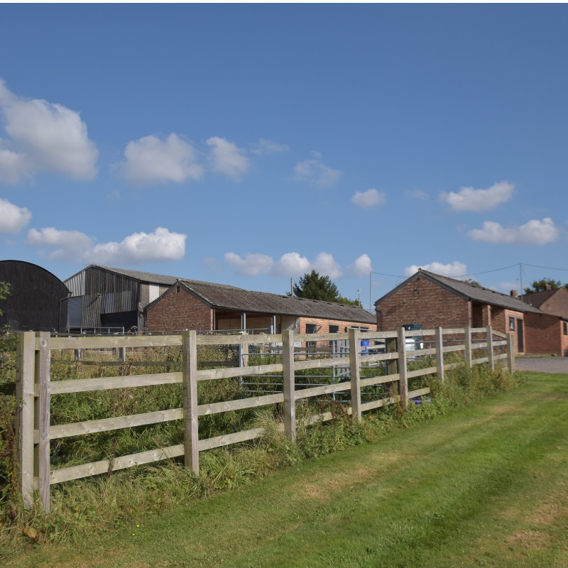A wooden fence with a barn in the background
