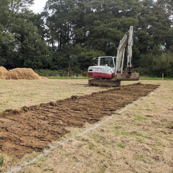 Digger removing turf from a grassed area