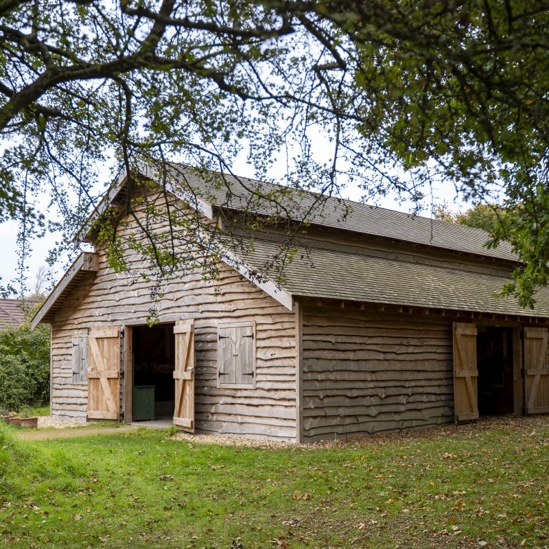Wood barn building with wide open doors in a woodland setting