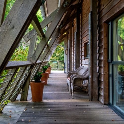A balcony with outdoor seating overlooking trees