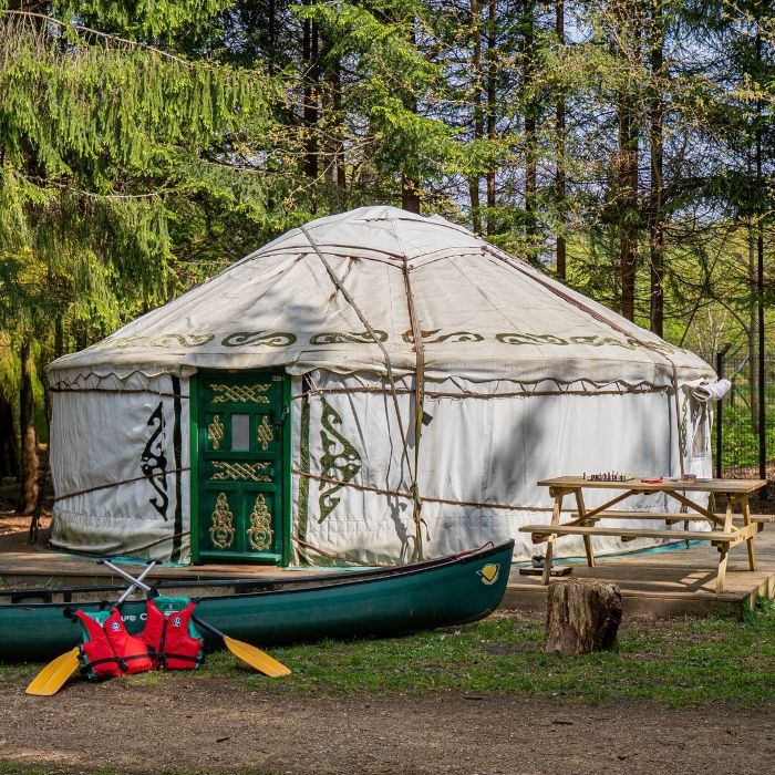 A yurt in the forest at Runway's End, with a canoe and picnic bench in front