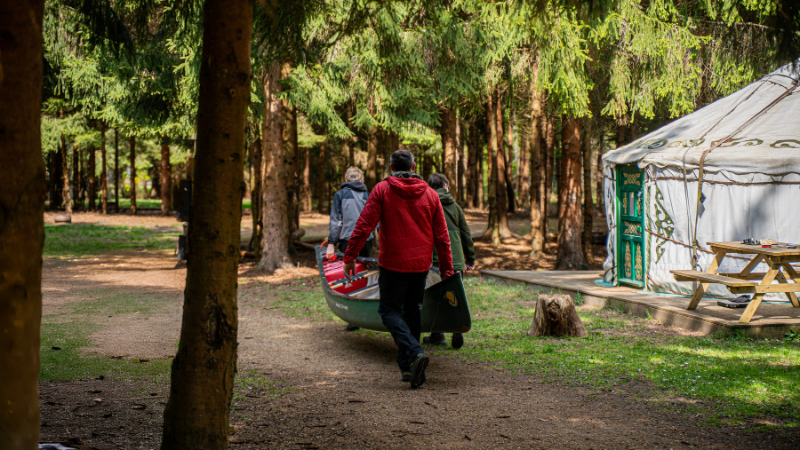A group carrying a canoe past the yurt