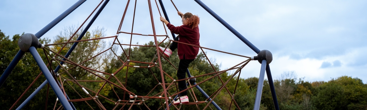 Child climbing up a rope climbing frame