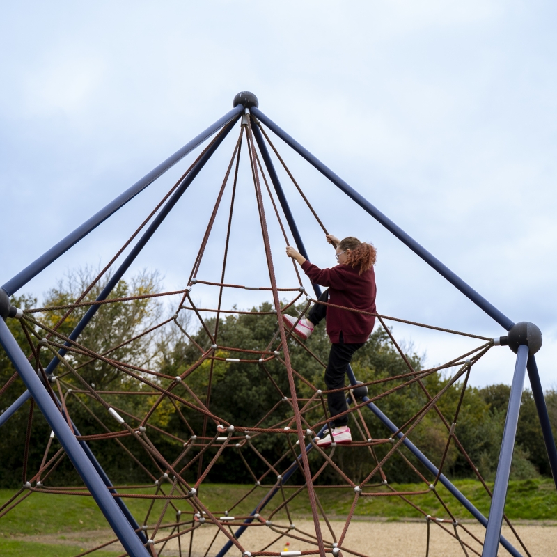 Child climbing up a rope climbing frame