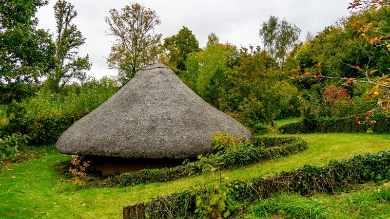 Small round hut with thatched roof nestled in landscaped garden