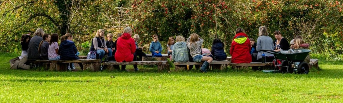 A group of students sitting at a long, outdoor bench