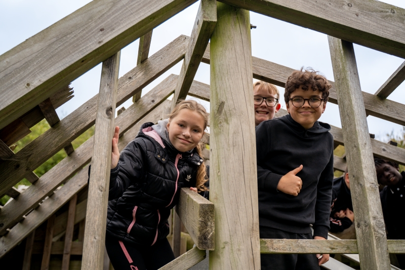 Children smiling from in a wooden climbing structure
