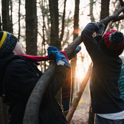 Children building a shelter with fallen branches