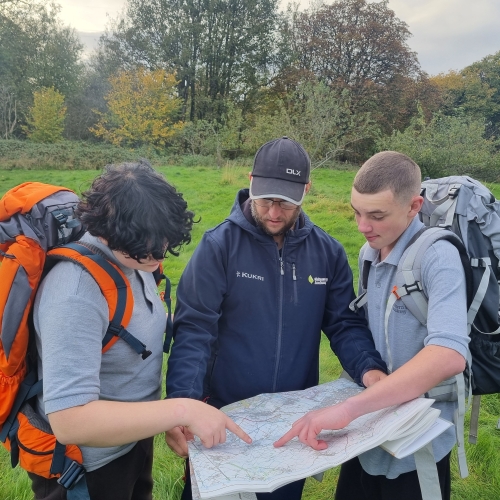 Students with backpacks studying a map with an instructor