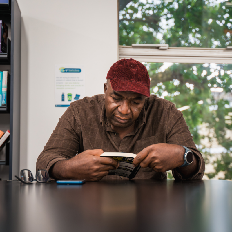 Man in a hat reading in a library