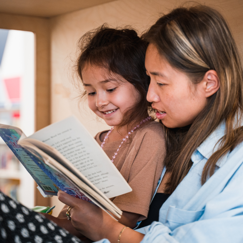 Woman and young girl reading a book together