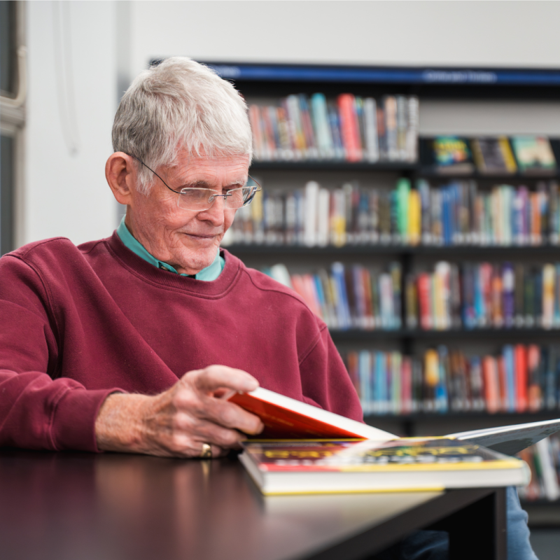 Older gentleman reading a book in a library