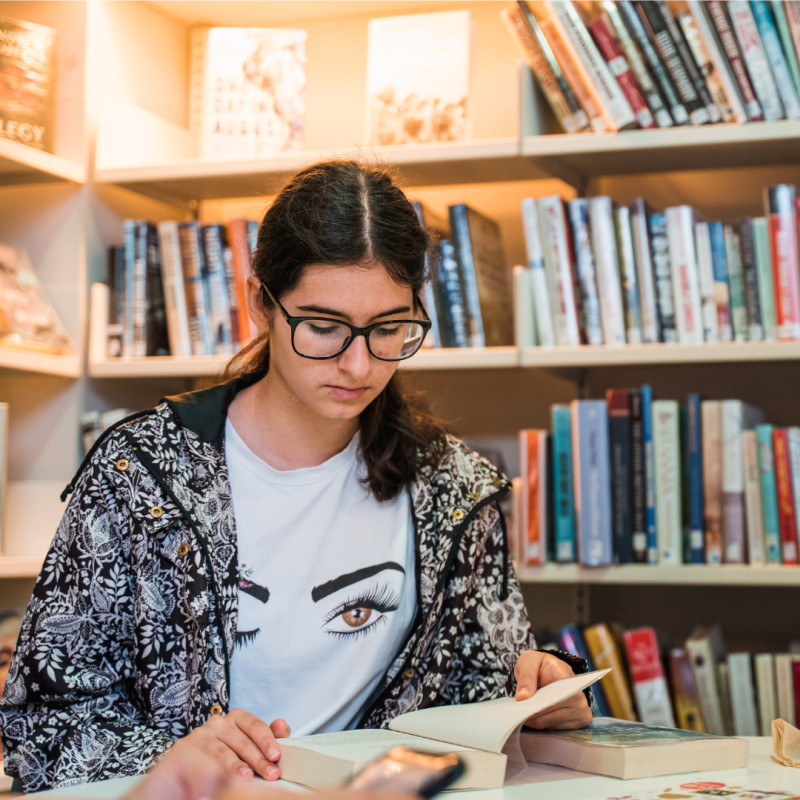 Teenage girl reading a book in a library