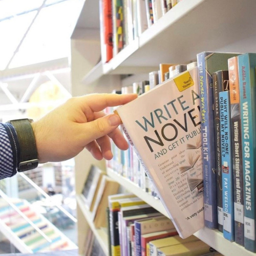 A person picking a book from a shelf