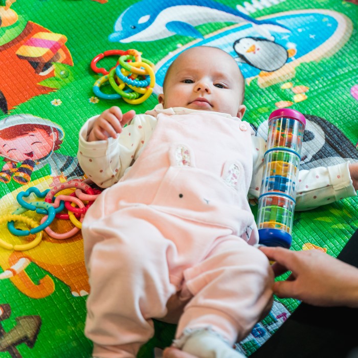 Baby on a play mat surrounded by toys